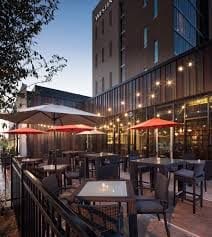 Outdoor patio dining at dusk with red umbrellas and string lights